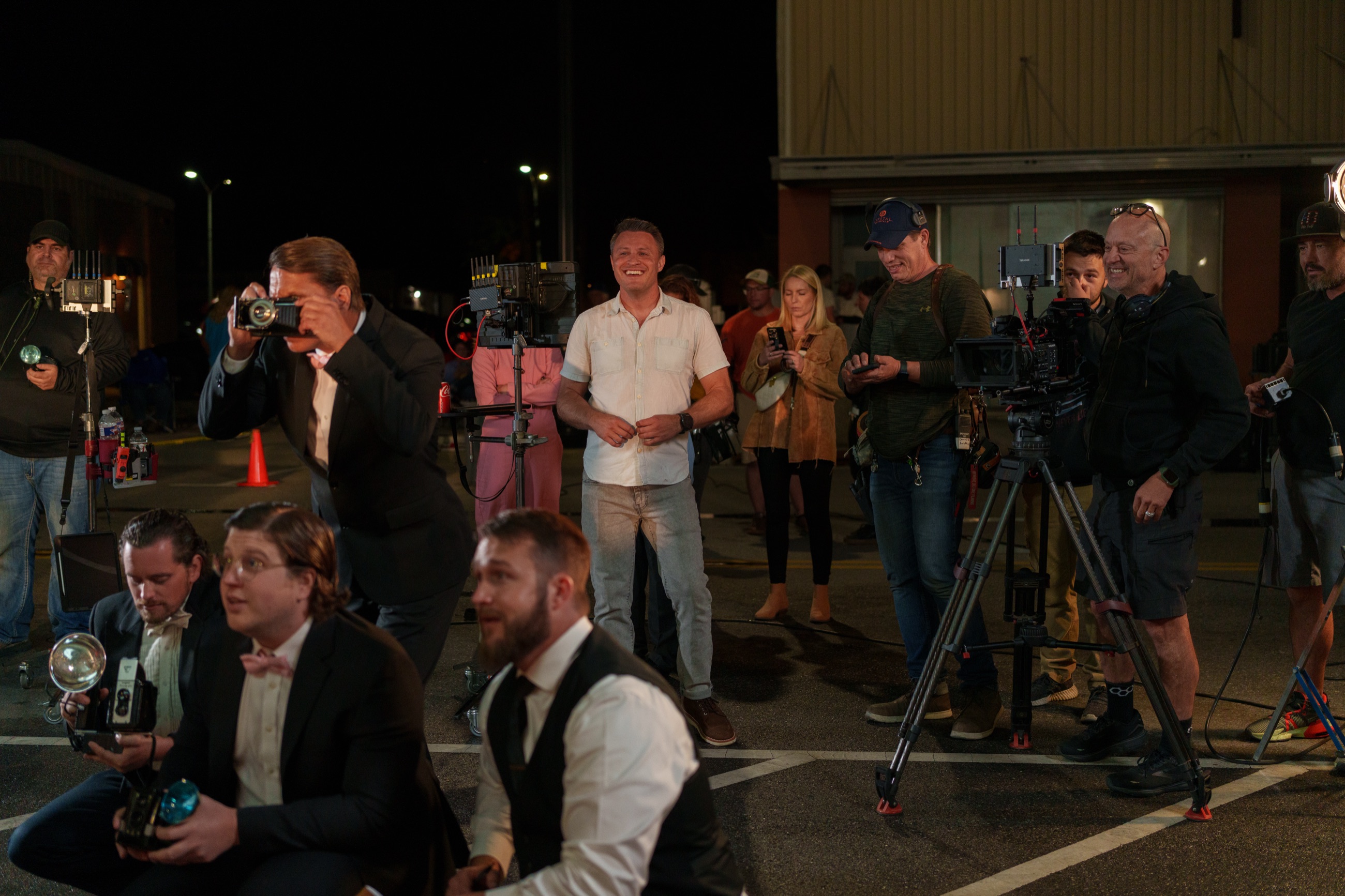 Jonathan Coussens on a night exterior set, surrounded by crew and period cast.